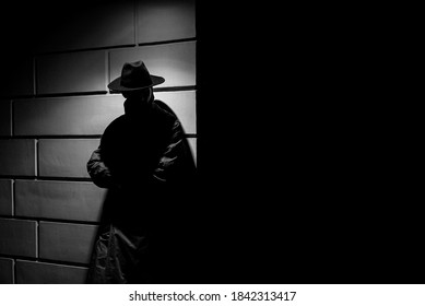 dark silhouette of a man in a raincoat with a hat at night on the street in a crime Noir style