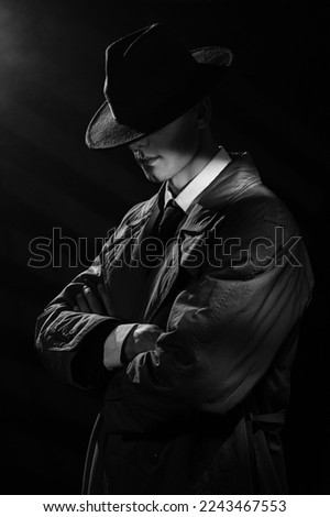 a dark silhouette of a man in a raincoat and hat with his head down in the style of crime noir. A dramatic noir portrait in the style of detectives of the 1950s.