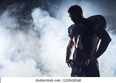 dark silhouette of thoughtful american football player looking down against white smoke - Powered by Shutterstock