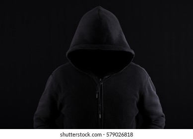 A dark and sinister figure in a hood against black. - Powered by Shutterstock