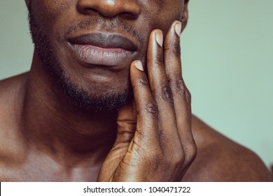 Dark skin Afro American African black man with hand touching face and chin thinking