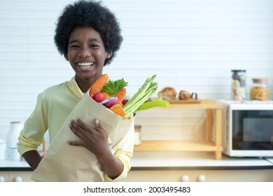 Dark Skinned Boy In The Kitchen And Holding Grocery Shopping Bag, Smile With Camera 