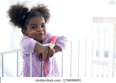 Dark skinned child girl eating ice cream stick 