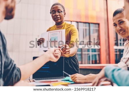 Dark skinned coach explaining paper diagram during lesson outdoors