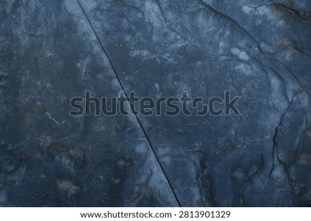 Dark slate stone surface displaying natural texture and rough cracking line