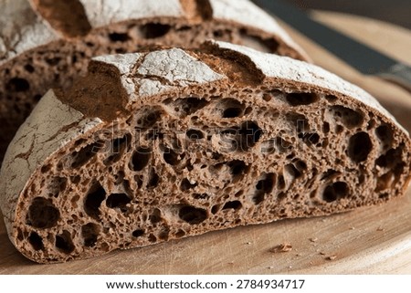 Dark Sourdough Bread : A thick rustic half-loaf of deeply fermented dark sourdough with an open irregular crumb and caramelized crust, a premium artisan European bread for bread enthusiasts.