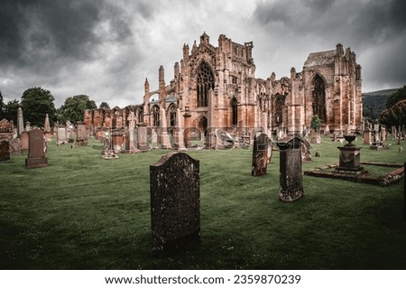 Dark and spooky Melrose Abbey cathedral in Scotland with graveyard and stone graves.