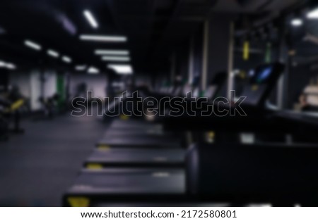 Dark sports fitness room with exercise machines and treadmills in defocus, blurred gym background,copy space for text