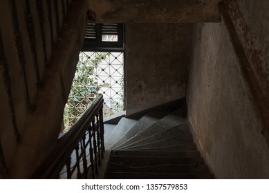 Dark Stair Descent In An Old House With Natural Light Coming From A Barred Window. The Mansion Or Villa Bodega, Phnom Penh, Cambodia.