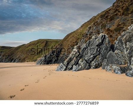 Dark stone cliffs of Silver strand, county Donegal, Ireland. Amazing Irish nature scenery. Rough rocks by a sandy beach. Nobody. Travel and tourism. Famous landmark.