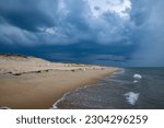 Dark storm clouds above the empty sandy beach.