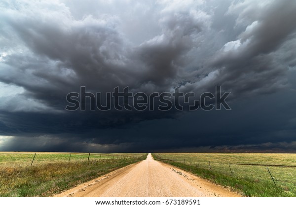Dark storm clouds and dirt\
road