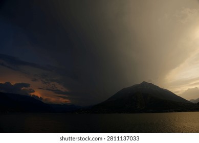 dark storm clouds form what looks like a huge funnel cloud in the distance during sunset over the mountains