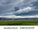 Dark storm clouds hover over a green meadow in Normany Park, Washington.
