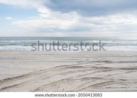 Dark storm clouds over a calm ocean at high tide with winds sweeping in land and carrying rain clouds precipitation over the beach sand in the cold winter months without tourists