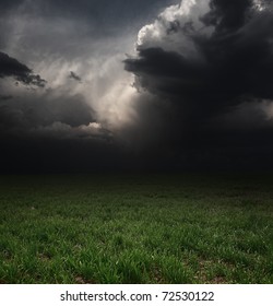 Dark Storm Clouds Over Meadow With Green Grass