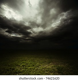 Dark Storm Clouds Over Meadow With Green Grass