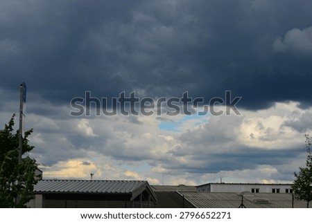 Dark storm clouds in the sky over the roofs of industrial or warehouse buildings