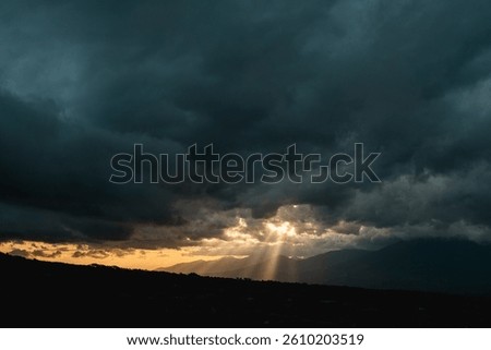Dark stormy sky with sun rays breaking through, perfect for dramatic backgrounds, weatherthemed designs, and expressing hope during difficult times.