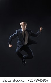 In a dark studio, a man in a sharp navy suit leaps mid-air, reaching upwards with determination. dynamic pose highlight ambition and success.