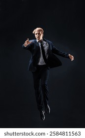 In a dark studio, a man in a sharp navy suit leaps mid-air, reaching upwards with determination. dynamic pose highlight ambition and success.