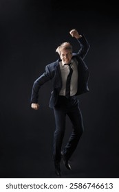 In a dark studio, a man in a sharp navy suit leaps mid-air, reaching upwards with determination. dynamic pose highlight ambition and success.