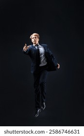 In a dark studio, a man in a sharp navy suit leaps mid-air, reaching upwards with determination. dynamic pose highlight ambition and success.