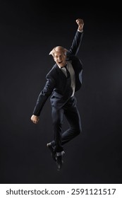 In a dark studio, a man in a sharp navy suit leaps mid-air, reaching upwards with determination. dynamic pose highlight ambition and success.
