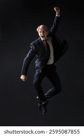 In a dark studio, a man in a sharp navy suit leaps mid-air, reaching upwards with determination. dynamic pose highlight ambition and success.