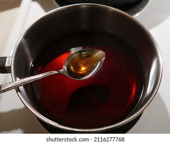 Dark syrup cooks in a metal pot. Homemade syrup. Trying a new recipe. Spoon full of sugar. - Shutterstock ID 2116277768