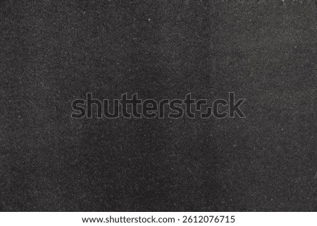 Dark textured black surface background with subtle grain.