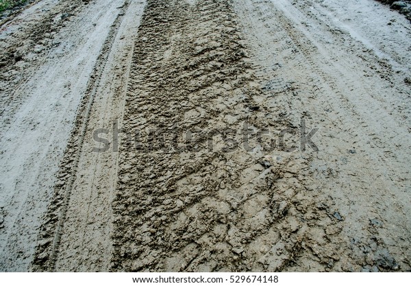 Dark tire tracks background Close-up\
tire tracks truck on a dirt road in daylight wheel\
track