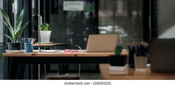 Dark tone office workplace. Wooden work desk with laptop and documents, modern interior of cozy cabinet,  comfortable workspace, workplace with computer in home. - Powered by Shutterstock