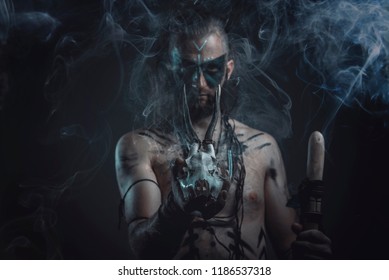 Dark tribal shaman or warlock summoning spirits using a deer skull and his ritual staff, halloween concept