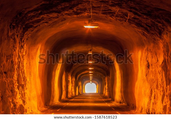 Dark tunnel in the mountain with\
lanterns. Typical tunnel in Norway on the Lofoten\
Islands.