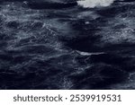 Dark, turbulent ocean waves crash and swirl, creating a dynamic, moody scene.