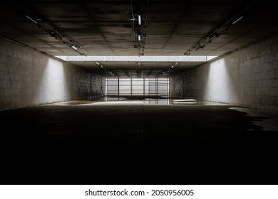 Dark underground empty dead end tunnel with light illuminated at the middle and fence at the end of the tunnel with copy space. Mystery, halloween, scary background concept.