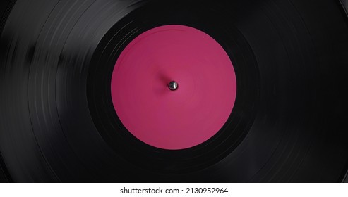 Dark vinyl background with a pink screen in the center. vinyl record on DJ turntable record player close up. Rotating or spinning plate and stylus with needle detail. - Powered by Shutterstock