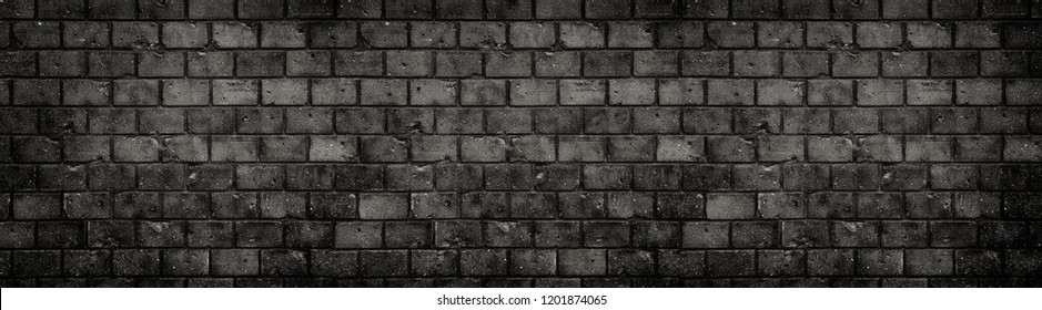 Dark wall. Old and weathered grungy black dark gray concrete block brick wall texture background with holes and cracks with vignetting in a large panoramic wide banner background