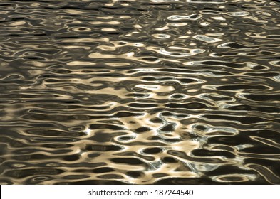 Dark water ripples catching the light of the sun