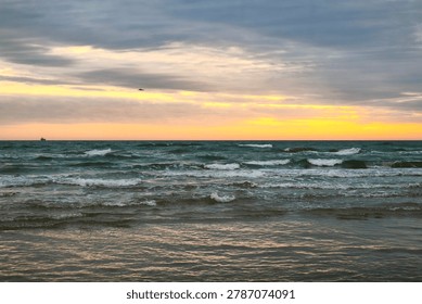 Dark waves and layered storm clouds meet a glowing sunset horizon, capturing the quiet power and emotional stillness of the sea before nightfall.