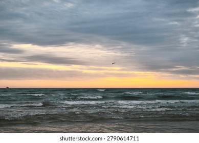 Dark waves and layered storm clouds meet a glowing sunset horizon, capturing the quiet power and emotional stillness of the sea before nightfall.