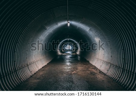 Dark & Wet corrugated iron tunnel with lighting under mountain