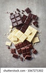 Dark, White And Milk Chocolate Pieces On Gray Marble Background. Top View