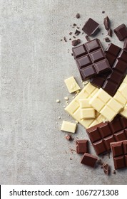 Dark, White And Milk Chocolate Pieces On Gray Marble Background. Top View