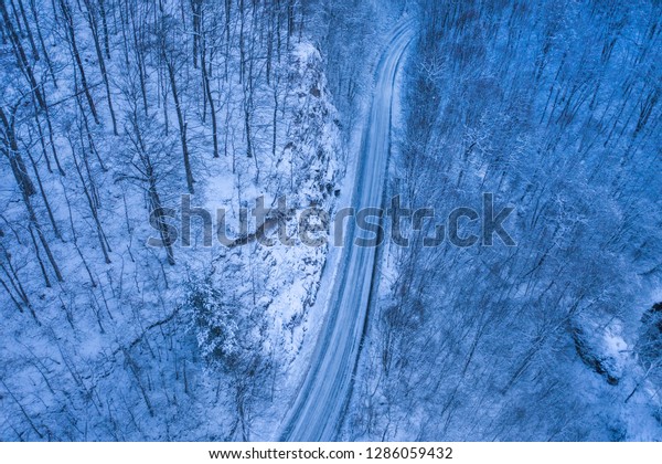 Dark winter road in the forest during blue hour.\
Aerial drone view