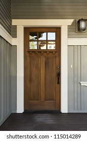 Dark Wood Front Door Of A Home. View Of A Rustic Front Door On A Light Gray Home During The Day. Vertical Shot.