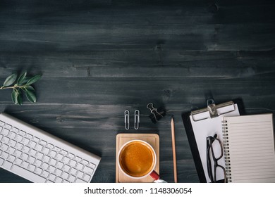 Dark Wood Office Desk Table With Blank Notebook, Supplies And Coffee Cup. Top View With Copy Space. Flat Lay.