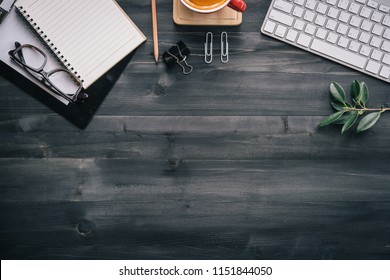 Dark Wood Office Desk Table With Blank Notebook, Supplies And Coffee Cup. Top View With Copy Space. Flat Lay.