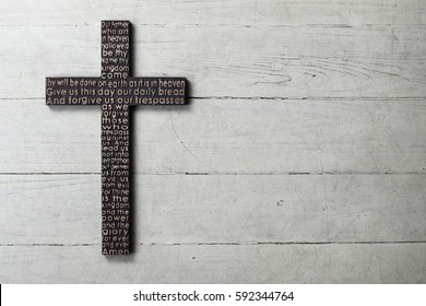 Dark wooden cross with carved the Lord's Prayer on worn white wooden background - Shutterstock ID 592344764